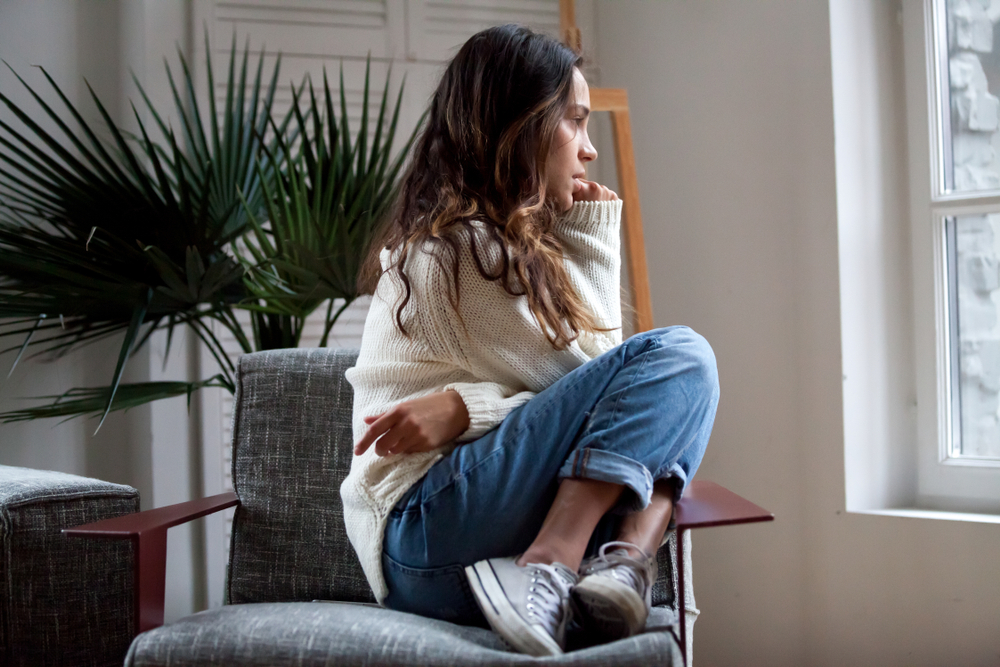 Teenage girl sitting on chair, looking uncomfortable