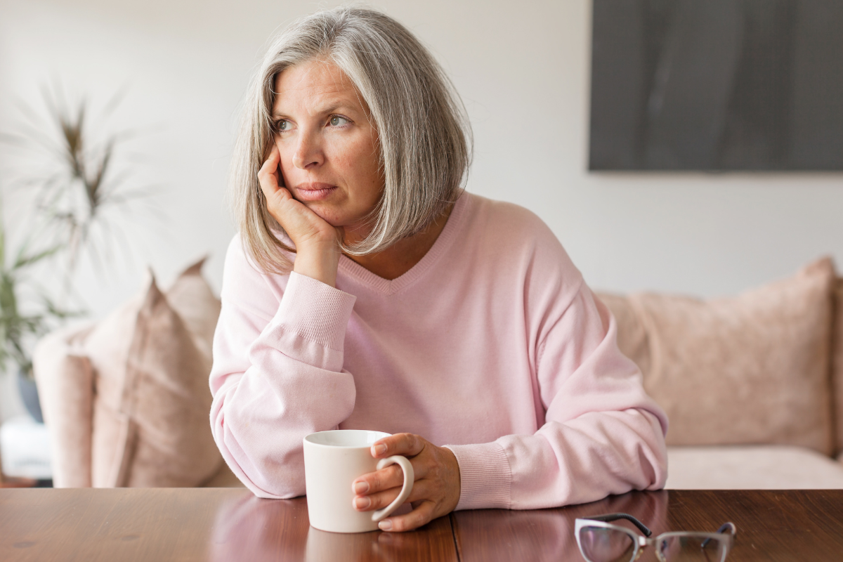 middle aged woman sitting at a desk wondering why she gets more UTIs after menopause